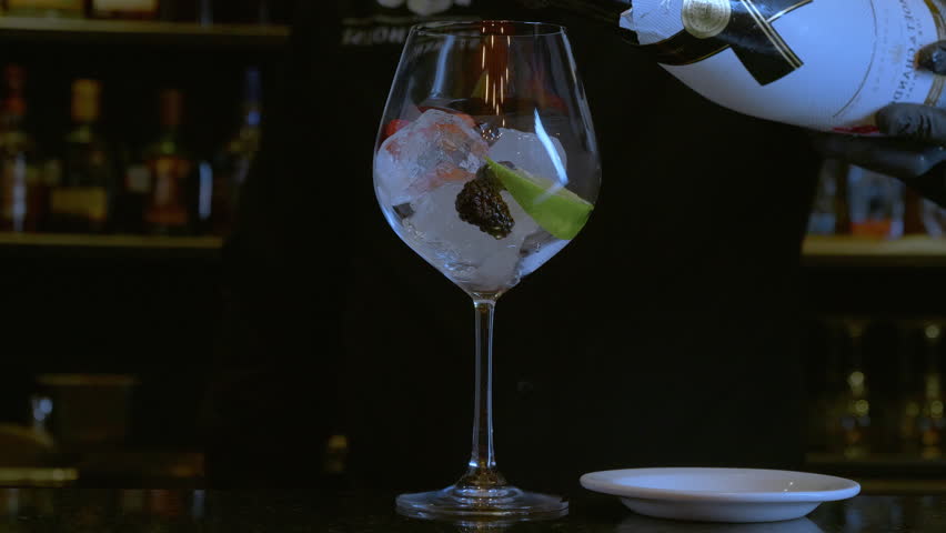 Mixologist pouring crafted cocktail into a wine glass at upscale bar, perfect for luxury lifestyle and mixology concepts.