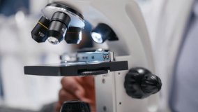 Close up of researcher focusing on a microscope with samples in chemistry lab. Using observation tool with tray for diagnostics, molecular analysis and discovery. Optics in bioscience. Camera B. - Powered by Shutterstock - Get 15% off with code: PIKWIZARD15