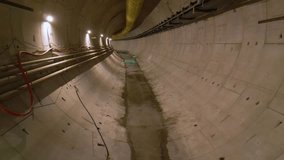 Underground metro tunnel interior during construction with concrete segment lining, utility cables, ventilation ducts, and dim industrial lighting in progress of large infrastructure engineering proje - Powered by Shutterstock - Get 15% off with code: PIKWIZARD15