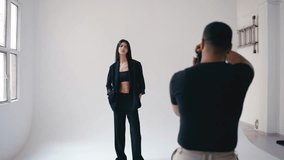 Professional photographer capturing fashion model's portrait during stylized photoshoot in modern white studio with digital camera and creative lighting setup - Powered by Shutterstock - Get 15% off with code: PIKWIZARD15