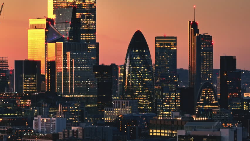 England, London: Aerial view of the illuminated London skyline during a vibrant sunset, showcasing famous landmarks and modern buildings, capturing the dynamic energy of the city's financial district