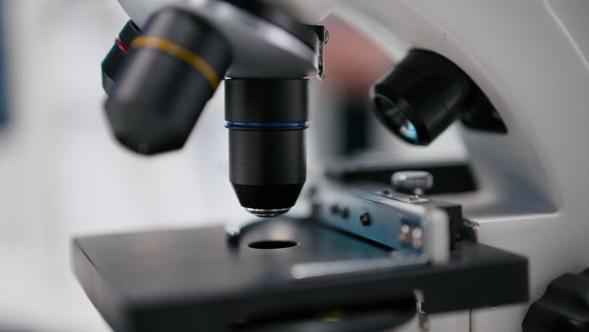 Microscope close up of specimen tray in lab studied by expert. Optical instrument, lens system and magnifying glass support cellular testing and biotechnology for healthcare. Bio science. Camera B.