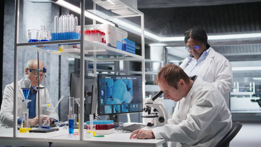 Employees team studying sample tray under the microscope for research study in a lab, cellular investigation and supporting genetics research. Advanced analysis for healthcare. Camera A.