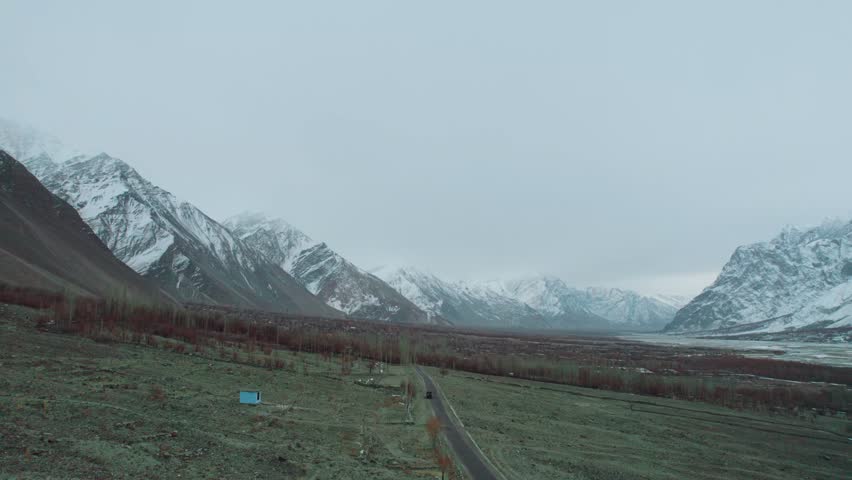 Beautiful drone view of road and valley in Gilgit Baltistan, Pakistan. Beautiful snow capped mountains, beautiful valleys, cloudy weather, spa nature, northern area of Pakistan, travelling, beauty. 
