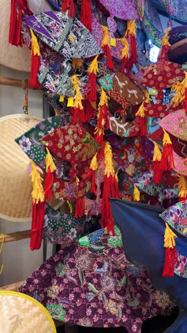 A vibrant collection of colorful batik wau placed against a bamboo frame for sale at the retail.