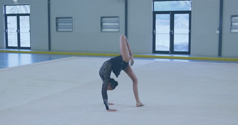 golden particles drifting in, gymnast arching into handstand then bowing ending fitness routine. Performance, flexibility, movement, elegance, sport, discipline, artistic