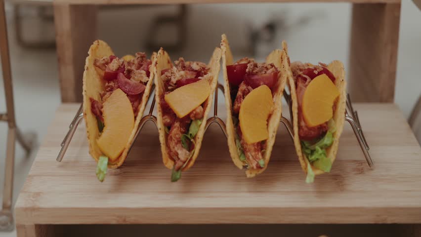 row of crispy tacos with meat cheese and fresh vegetables on wooden stand