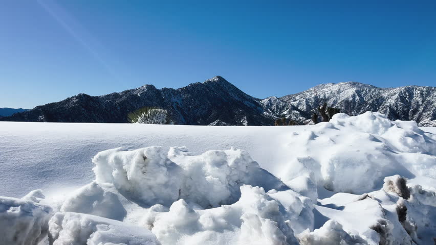 Beautiful snow-covered landscape at San Gabriel River, Los Angeles, clear blue sky and mountains in background.