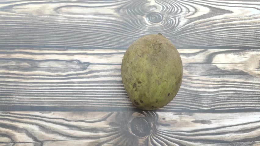 The right hand holds a Mangifera foetida or Pakel or Bacang which is is a tropical mango relative. This fruit is distinct for its pungent aroma and fresh sour or sweet and sour taste.