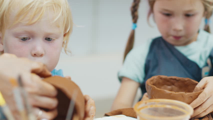 Women with kids create hand made cups from the clay and learn pottery on the pottery masterclass
