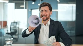 Excited businessman in a suit jacket announces good news. Professional male in a modern office shouts into a megaphone, showing fan of money, celebrating financial success. - Powered by Shutterstock - Get 15% off with code: PIKWIZARD15