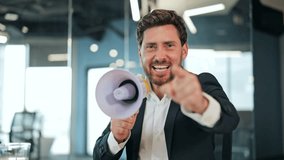 Energetic businessman in a suit and white shirt shouts into a megaphone in a modern office, expressing excitement and determination while pointing. - Powered by Shutterstock - Get 15% off with code: PIKWIZARD15