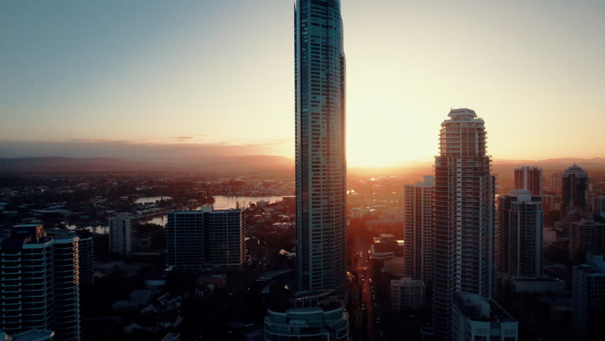 Drone footage capturing the skyscrapers of Surfers Paradise with a dramatic sunset backdrop, blending natural beauty with urban architecture.