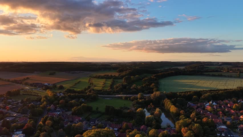 Vibrant peaceful sunset time over small American town in late summer. Aerial wide shot. Houses and homes with Traffic on rural highway and roundabout. Colored sky in the evening.