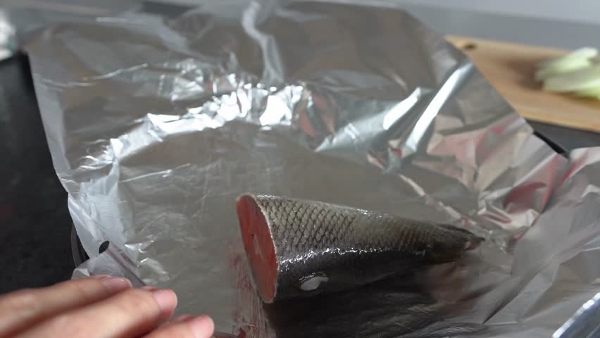 A woman cooks pink salmon in foil. Close-up. Healthy eating.