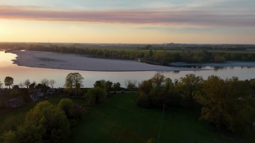 A drone shot captures the River Po winding past the Maginot and Bodri fields under a stretched stratocumulus cloud, painting soft layers across the sky during golden sunset over farmland, slow motion