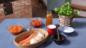 A colorful arrangement of fresh ingredients prepared for cooking tomato soup. The table displays carrots, onions, garlic, chili, tomatoes, oil, vinegar, herbs, salt, and broth on a rustic blue cloth. - Powered by Shutterstock - Get 15% off with code: PIKWIZARD15