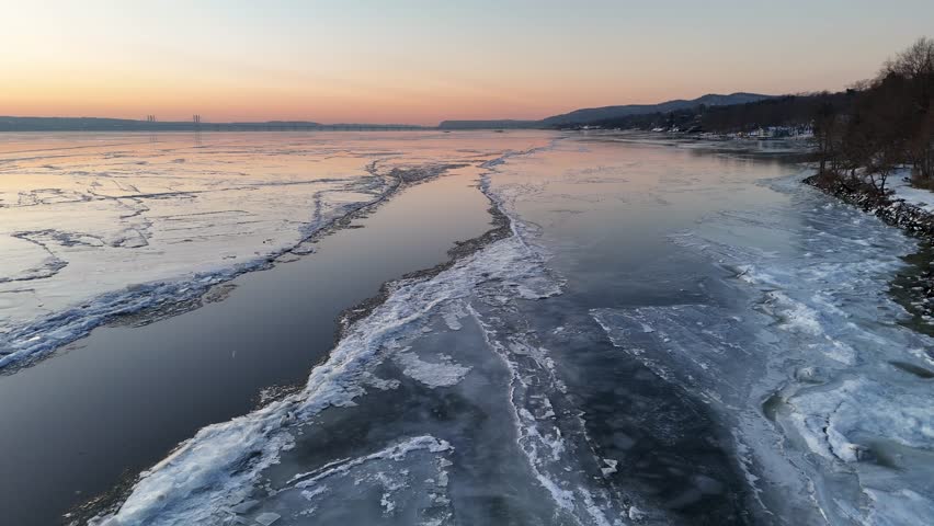 Aerial view of the icy Hudson River reflecting the soft dawn colors, where fractured ice meets the calm water, Hudson River, United States.