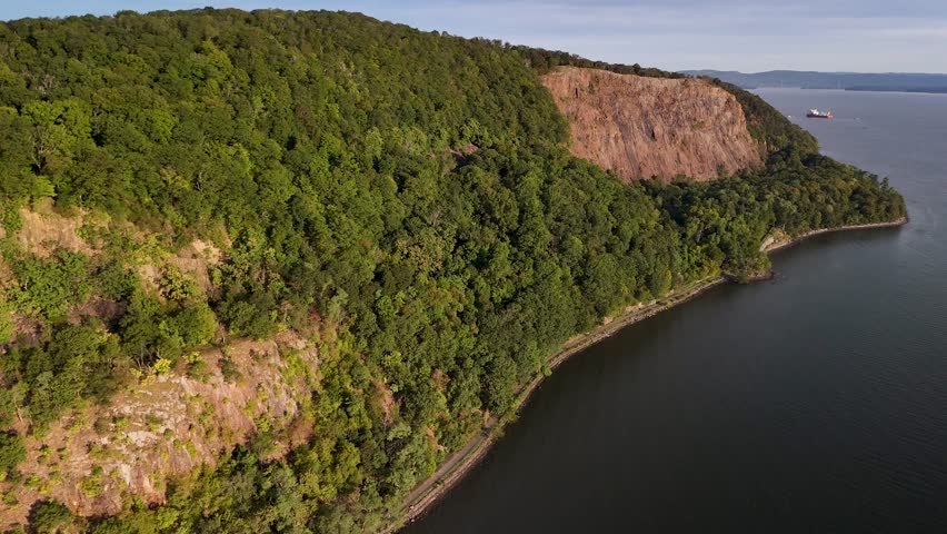 Aerial view of the vibrant green cliffs contrasted against the dark waters of the Hudson River, creating a serene landscape, Hudson River, United States.