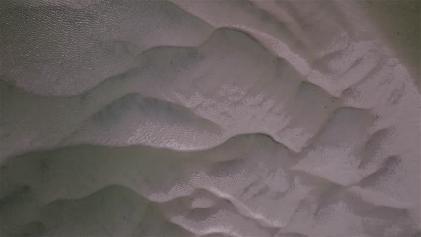 Aerial view of sand formations in clear, shallow, water creates a mesmerizing pattern of textures and tones: a natural artistic display. Gray
