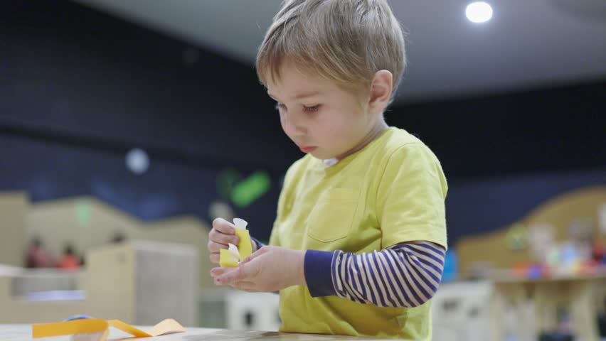 Focused little boy engaged in crafting with paper
