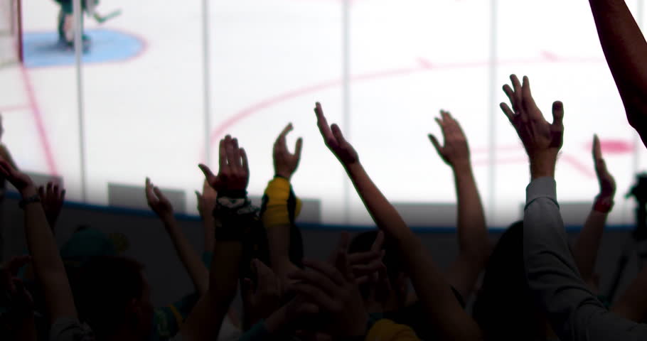 Cheering crowd silhouettes celebrate a victory at an ice hockey game.