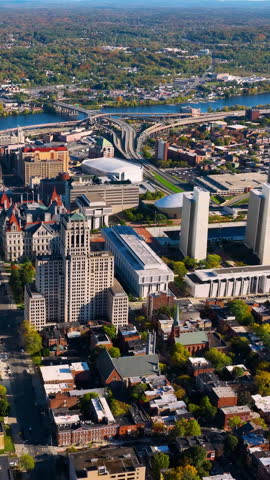 Albany Empire State Plaza and Capitol complex stand out in this aerial view, framed by tree-lined streets and the Hudson River. Vertical video.