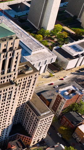 Aerial view of Albany, New York showing a mix of modern and historic buildings, includes tall office structures, smaller brick buildings, tree-lined streets, and green spaces. Vertical video.