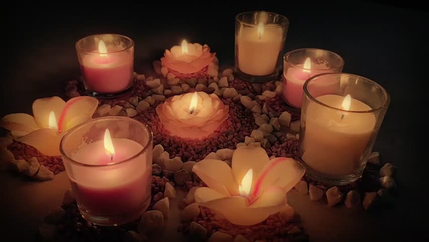 Little touch of magic  Glowing candles in different shapes and colors create a beautiful atmosphere. Underneath, stones arranged like a flower highlight the play of light and color even more.