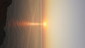 Golden sunset over calm sea reflects on water near rugged coast, tranquil coastal scene. vertical video - Powered by Shutterstock - Get 15% off with code: PIKWIZARD15