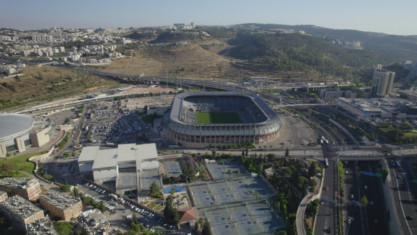 Teddy Stadium’s Jerusalem, israel empty grandeur in this high-altitude parallax shot, emphasizing warm light on clean architectural lines