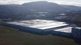 Warehouse Building in Industrial Park Processing Orders with Bright Sunlight with Mountains in Background. Manufacturing Plant Processing Raw Materials into Finished Product. - Powered by Shutterstock - Get 15% off with code: PIKWIZARD15