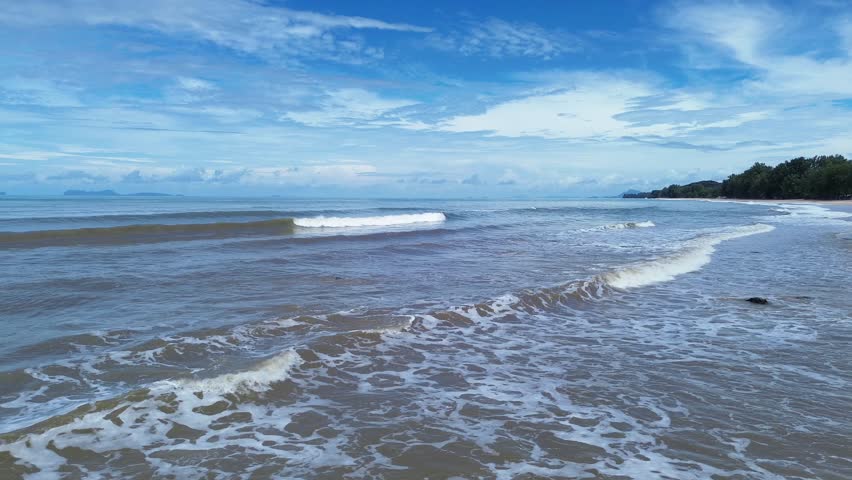 Drone aerial of Long Beach shoreline in Thailand, featuring a scenic coast with dense pine forest and scattered palm trees along sandy beach and turquoise sea under tropical sunlight.