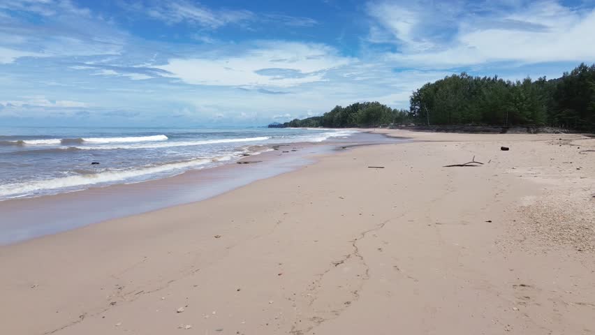 Drone aerial of Long Beach shoreline in Thailand, featuring a scenic coast with dense pine forest and scattered palm trees along sandy beach and turquoise sea under tropical sunlight.