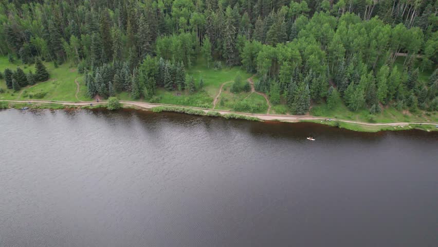 Aerial video of Lake Isabel in Rye, Colorado. Camera pans left showing the shoreline.