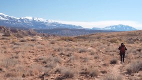 Solitary Woman With Backpack Waking on Trail in Desert Landscape With Snow Capped Mountains on Horizon - Powered by Shutterstock - Get 15% off with code: PIKWIZARD15
