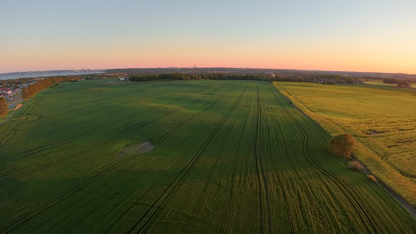 Aerial drone footage of expansive farmland fields at sunset with warm golden light and rural scenery.