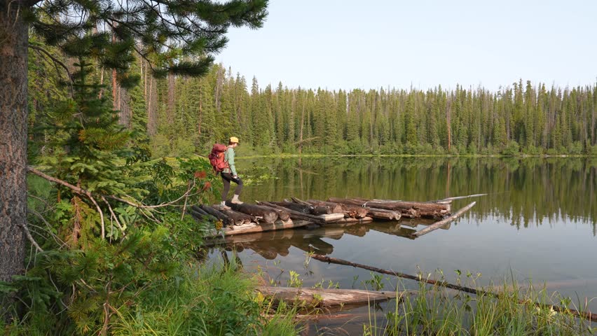 Lonely Female Hiker With Backpack Walking on Wooden Platform on Pristine Alpine Lake, White River National Forest and Lost Lake, Colorado USA