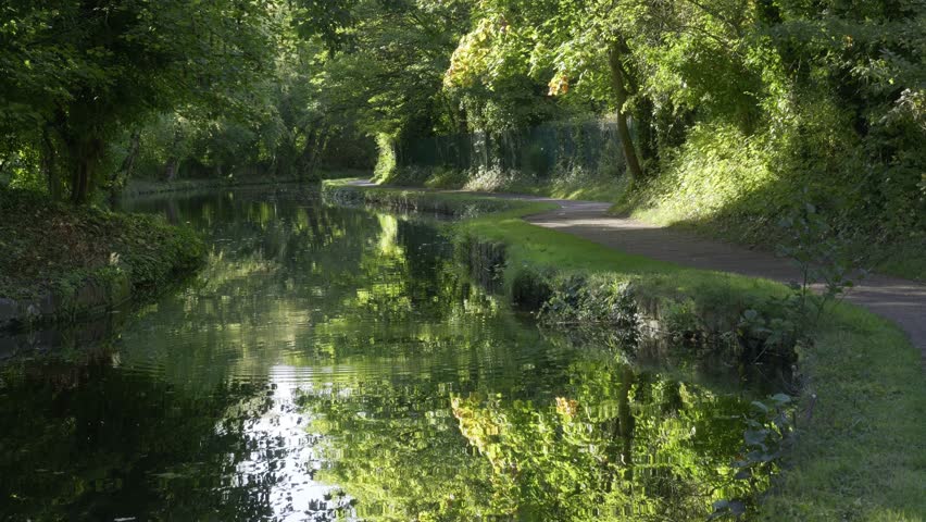 Cyclist Riding Along Tree-Lined Canal Towpath in Birmingham, UK.
A cyclist rides along the towpath of the Birmingham to Worcester Canal near Birmingham University.