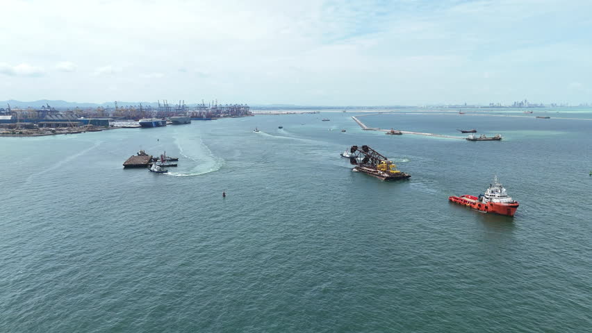 Aerial view of tugboats towing a large rusty steel barge in the ocean, used for transporting heavy industrial cargo or offshore construction. Maritime logistics and shipping concept.