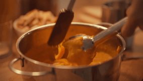 A hand stirs a pot of creamy pumpkin soup in a warm kitchen filled with the scent of spices. Friends gather around, preparing for a cozy autumn meal with laughter and conversation - Powered by Shutterstock - Get 15% off with code: PIKWIZARD15