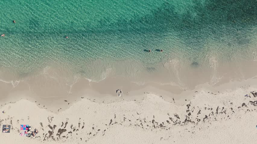 Aerial Footage From Nova Scotia Showing Clear Blue Waters Of The Atlantic, With People Floating, Walking, And Enjoying Summer Sunshine On The Sandy Shoreline In Peaceful Setting.