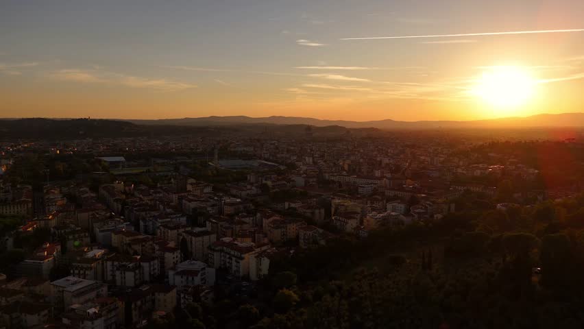 Cinematic drone sunset view over Florence rooftops, golden hour light casting warm glow on red terracotta roofs, panoramic urban landscape, aerial perspective, Italy cityscape