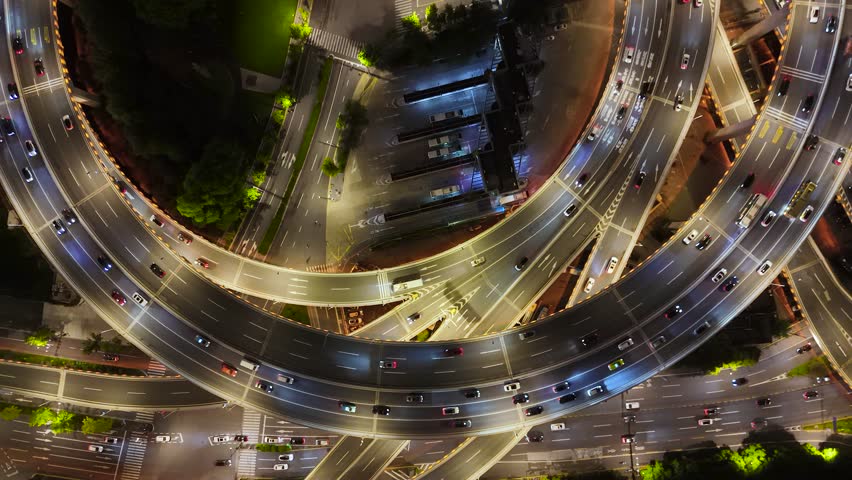 Aerial view of a complex multi-level highway interchange with heavy night traffic and illuminated roads in Shanghai, China.