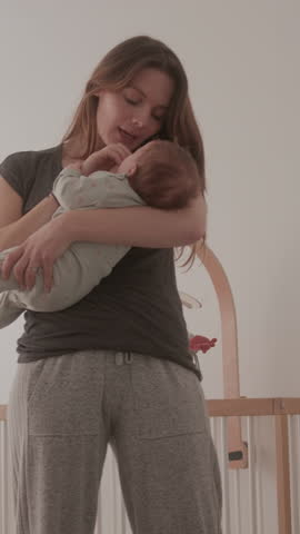 New Mum Cradling her Baby trying to get to Sleep in Nursery at Home