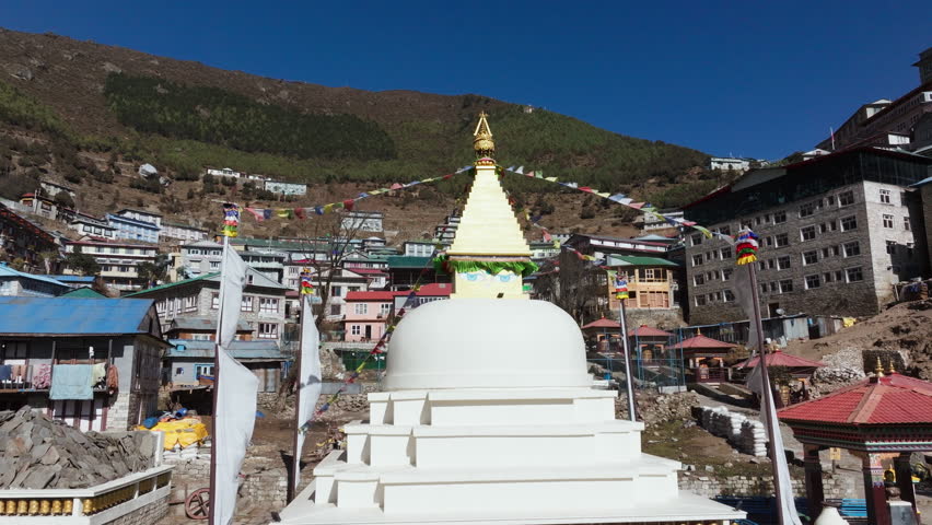 Aerial View of a Traditional Nepali Village in the Himalayas, Featuring a Majestic Stupa and Colorful Prayer Flags