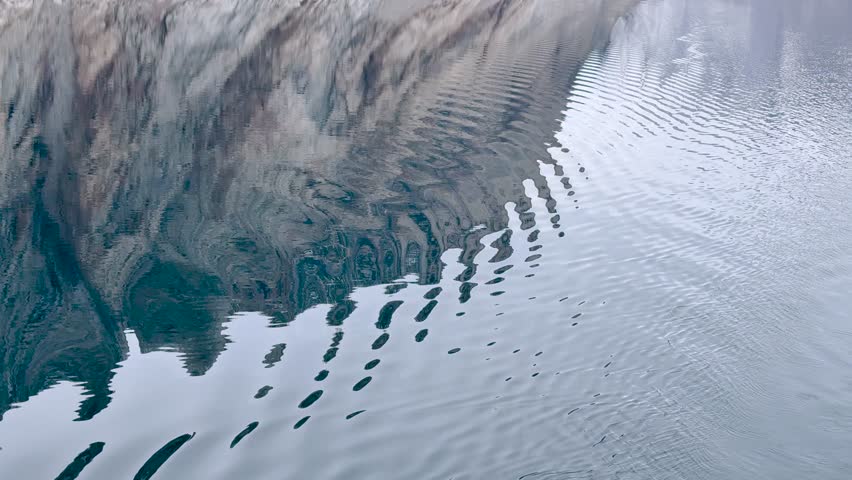 Calm water reflects nature surrounding it, creating a beautiful and peaceful view. The light dances on the surface, enhancing the tranquility of the scene.