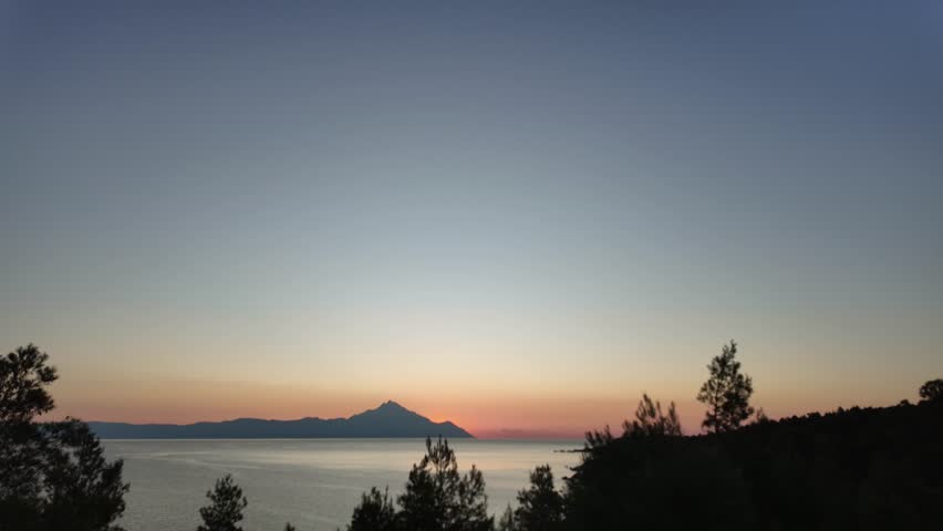 Time Lapse of Sunrise Over the Sea with Rocks Silhouetted Against a Bright Sky