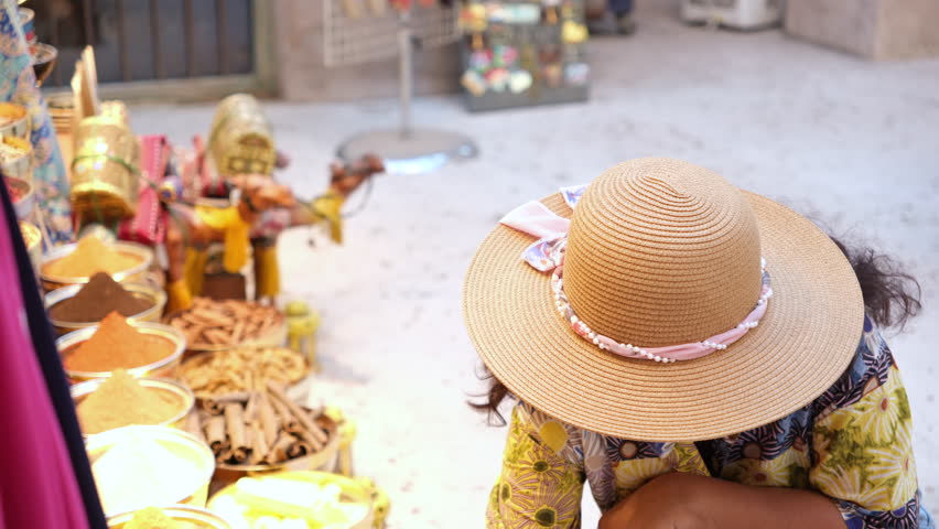Tourist woman in hat exploring spice market at Souq Waqif Doha Qatar smelling traditional spices and herbs, 4k pro resolution travel and lifestyle video