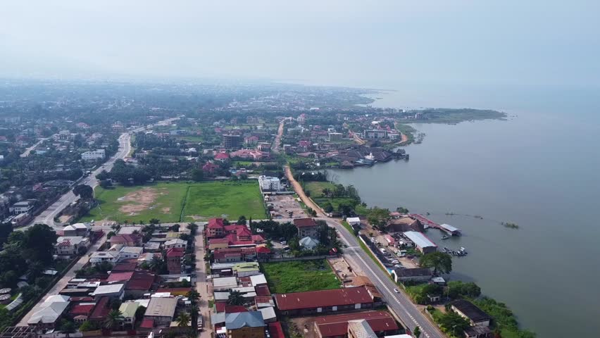 This overhead shot captures a coastal city, where buildings and roads meet the vast expanse of water. The scene blends urban development with natural beauty harmoniously.